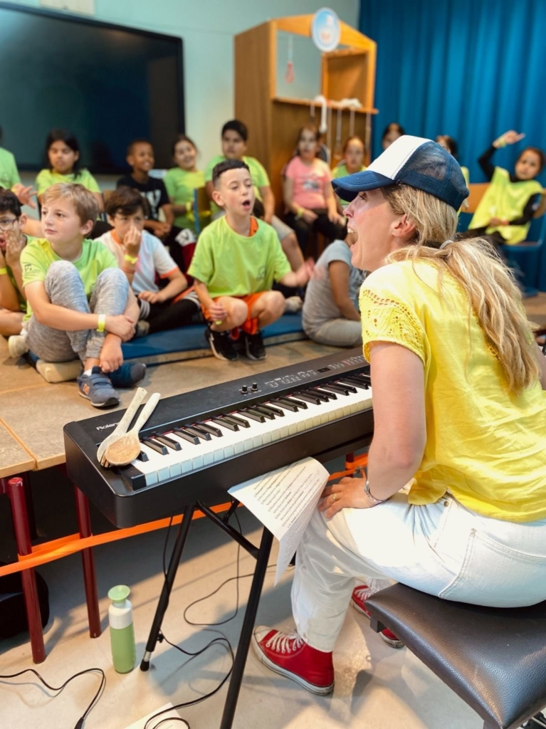 Jorieke achter de piano met de Boosters-kinderen